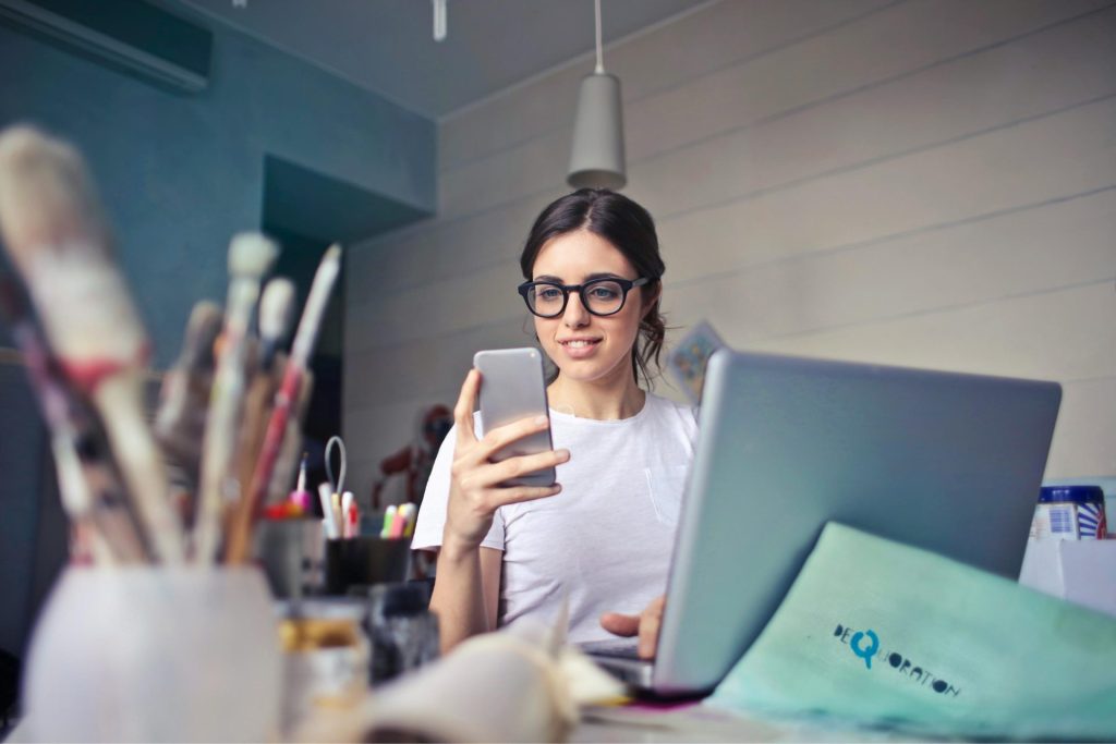 Mujer usando teléfono y computadora

